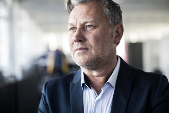 Thoughtful Mature Businessman Looking Away In Office