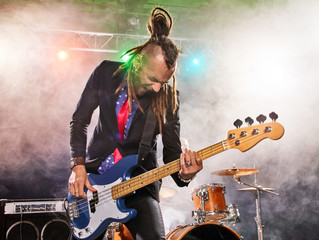 Rock band performs on stage. Bassist in the foreground. Close-up.