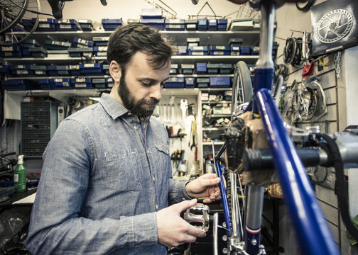 Mid adult repairman repairing bicycle at workshop