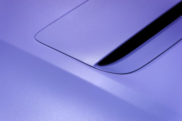 Fragment of sport car hood with air intake, vehicle steel bodywork, violet paint coating texture,...