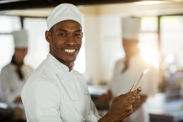 Portrait of smiling chef using digital tablet