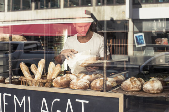 View of mid adult male owner working at bakery through display cabinet