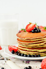 
easy hearty and healthy breakfast , American pancakes with berries , blueberries and strawberries with milk on a wooden background
