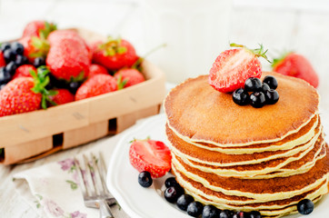 
easy hearty and healthy breakfast , American pancakes with berries , blueberries and strawberries with milk on a wooden background