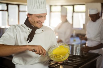 Smiling chef mixing dough