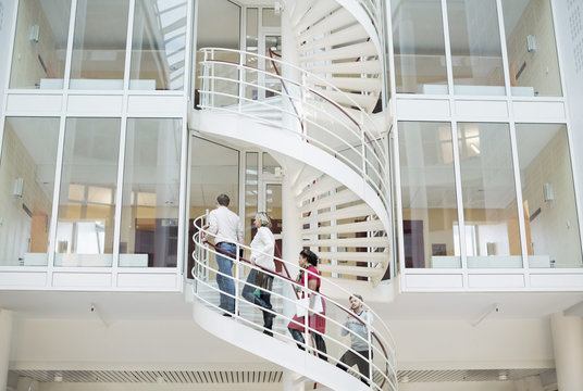 Business people climbing spiral staircase in office