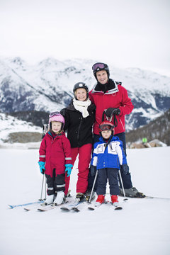 Portrait of family in ski-wear standing together against mountain range