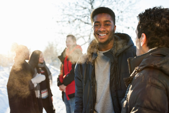 Young men in warm clothing with friends communicating in background