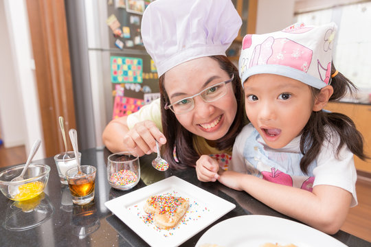 Asian mother and daughter enjoy making pancake in kitchen