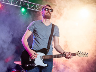 Rock band performs on stage. Guitarist.