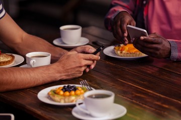 Cropped image of friends eating pastries and drinking coffee