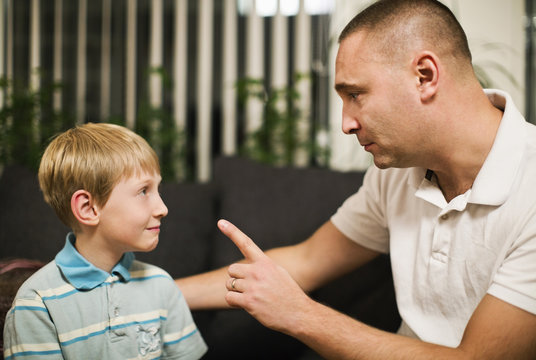 Angry mid adult man disciplining son at home
