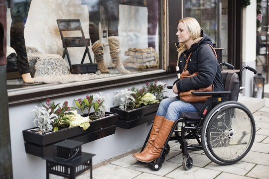 Disabled woman in wheelchair looking in store window