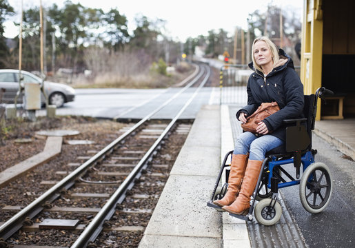 Disabled woman in wheelchair waiting for the train at railway station