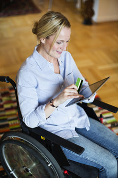 Disabled woman in wheelchair using digital tablet for online shopping