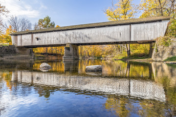 Fototapeta na wymiar Historic covered bridge crosses Sugar Creek at Darlington, Indiana with colorful autumn foliage surrounding.