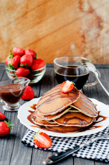 Obraz na płótnie Canvas easy hearty and healthy breakfast , American pancakes with strawberries and chocolate with coffee on a wooden background