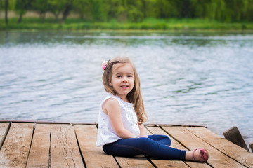 Fototapeta na wymiar emotions of a little girl on beautiful wooden pier