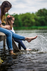 mom with little girl on wooden pier and wet feet