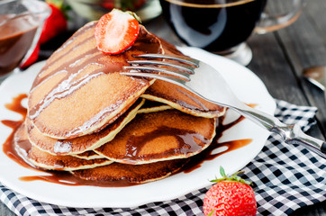 
easy hearty and healthy breakfast , American pancakes with strawberries and chocolate with coffee on a wooden background