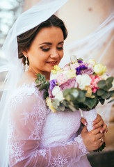 beautiful bride closeup portrait under a veil. Bride with flowers boquet. Near columns.