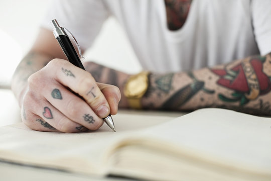 Midsection of a tattooed man writing