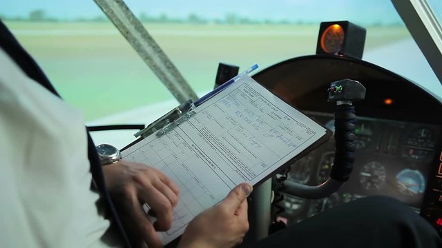 Light aircraft pilot preparing for takeoff, checking flight route in documents