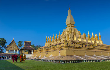 Naklejka premium Group of Buddhist monks walking around That Luang Stupa, landmark of Vientiane, Lao PDR