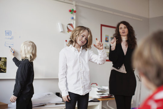 Teacher looking at children while playing guess game in classroom