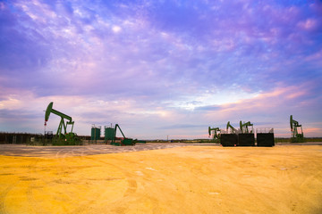 Fototapeta premium Silhouette of Oil pumps at oil field with sunset sky background