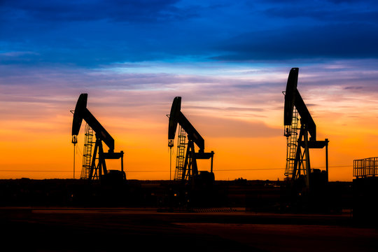Silhouette of Oil pumps at oil field with sunset sky background