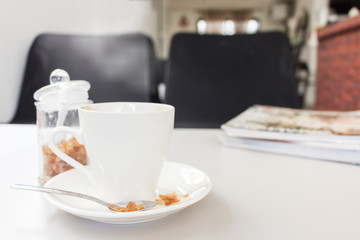 cup of coffee and sugar with magazine on white wood table
