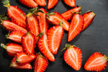 top view copyspace, strawberries cut into pieces on black backgr