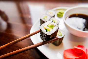 Rolls in nori seaweed with avocado, pickled ginger and soy sauce. Asian cuisine, traditional dish - sushi.