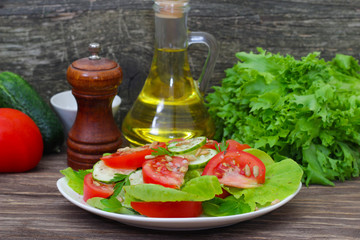 Fresh salad with tomatoes, cucumbers and lettuce on a wooden background
