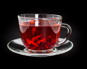 Cup of red hibiscus tea on black background