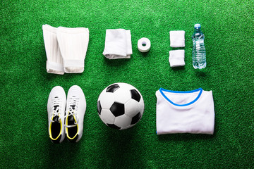 Soccer ball,cleats and various football stuff against artificial