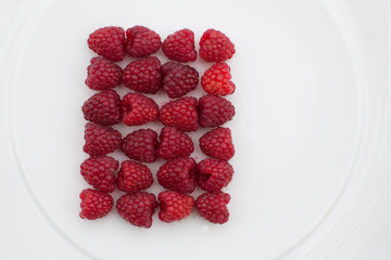 Square pattern of red raspberries, overhead from above, isolated on white background