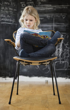 Girl sitting in chair and reading book