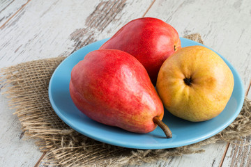 Juicy ripe pears.   Juicy ripe pears on a blue plate on a burlap on a light wooden background.