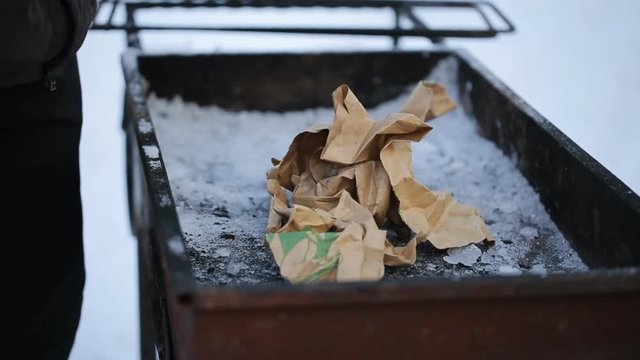 A man collects bonfire of paper of sticks in grill winter.
