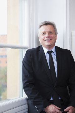 Portrait of businessman holding mobile phone looking at camera