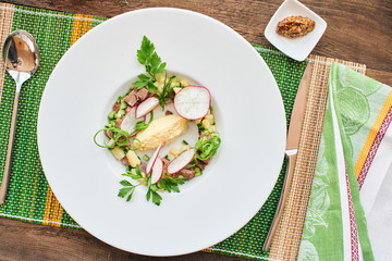 Top view of the blank for okroshka with beef in white plate on wooden table