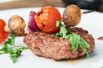 Steak and vegetables on skewers, served on a white plate