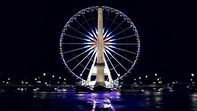 Illuminated roue de Paris and the Obelisk of Louxor at night in Paris