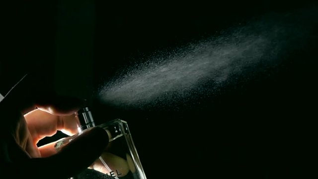 Spraying perfume against black background super slow motion dolly shot