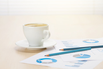 Office workplace with coffee, supplies and reports