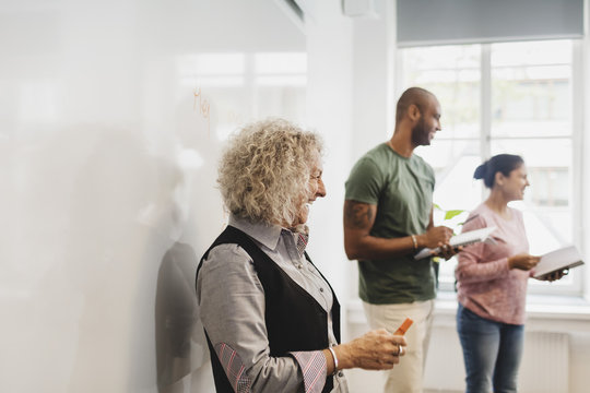 Smiling students standing by teacher against whiteboard in language class