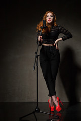 Fototapeta na wymiar Portrait of beautiful singer in red heels and black clothes