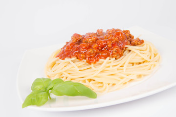 Spaghetti bolognese decorated with basil on a white background